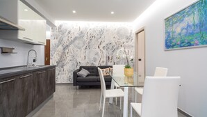 A modern kitchen with dark cabinets, a glass dining table, and a gray sofa. - Apartment "Dharma" with Mountain View, Terrace & Wi-Fi (Giardini-Naxos)