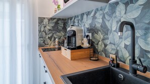 Una cocina moderna con encimera de madera, un lavamanos negro, una cafetera y un microondas en un estante.