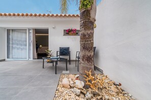 Un patio con una palmera, asientos y un adorno de coral.