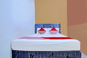 A bed with a patterned headboard, white bedding, and red and white pillows. - OYO 90476 Iksan Homestay Syariah (Prabumulih)