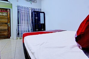 A bedroom with a bed, a wooden door, and a window with curtains.