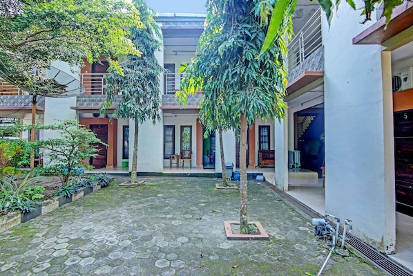 A courtyard with a tiled floor, potted plants, and a staircase leading to an upper level.