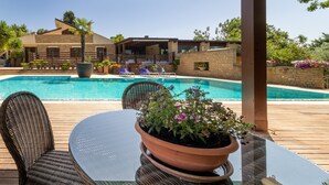 A poolside area with a covered seating area, a table, and a potted plant. - Apartment 'Giusa' with Shared Pool, Wi-Fi and Air Conditioning (Caltagirone)