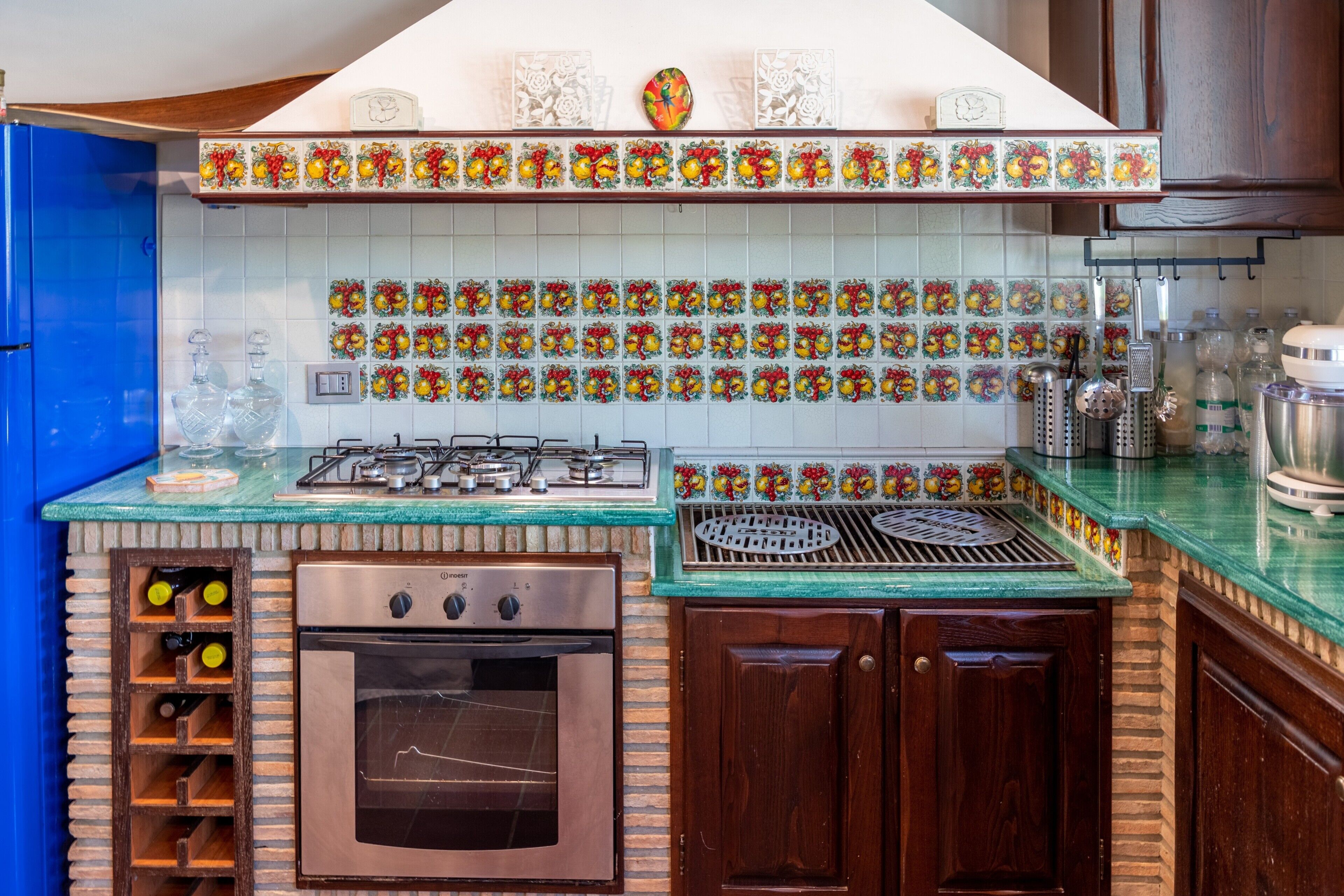 A kitchen with a gas stove, oven, and wine storage.