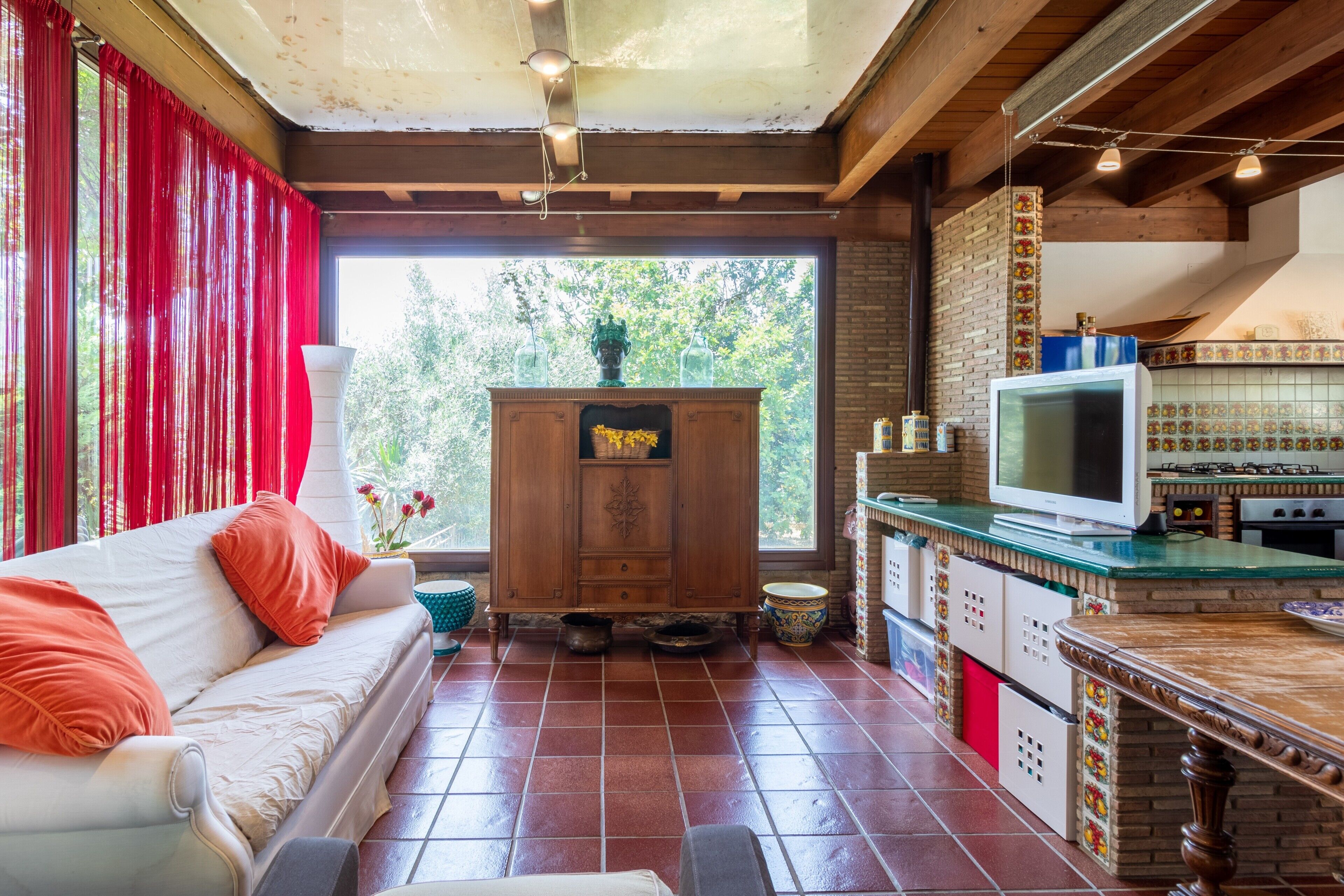 A cozy living area with a sofa, a television, and a kitchen area with a tiled backsplash.