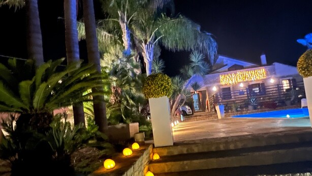 A nighttime view of a building with a stone pathway leading to a brightly lit entrance. - Apartment 'Giusa' with Shared Pool, Wi-Fi and Air Conditioning (Caltagirone)