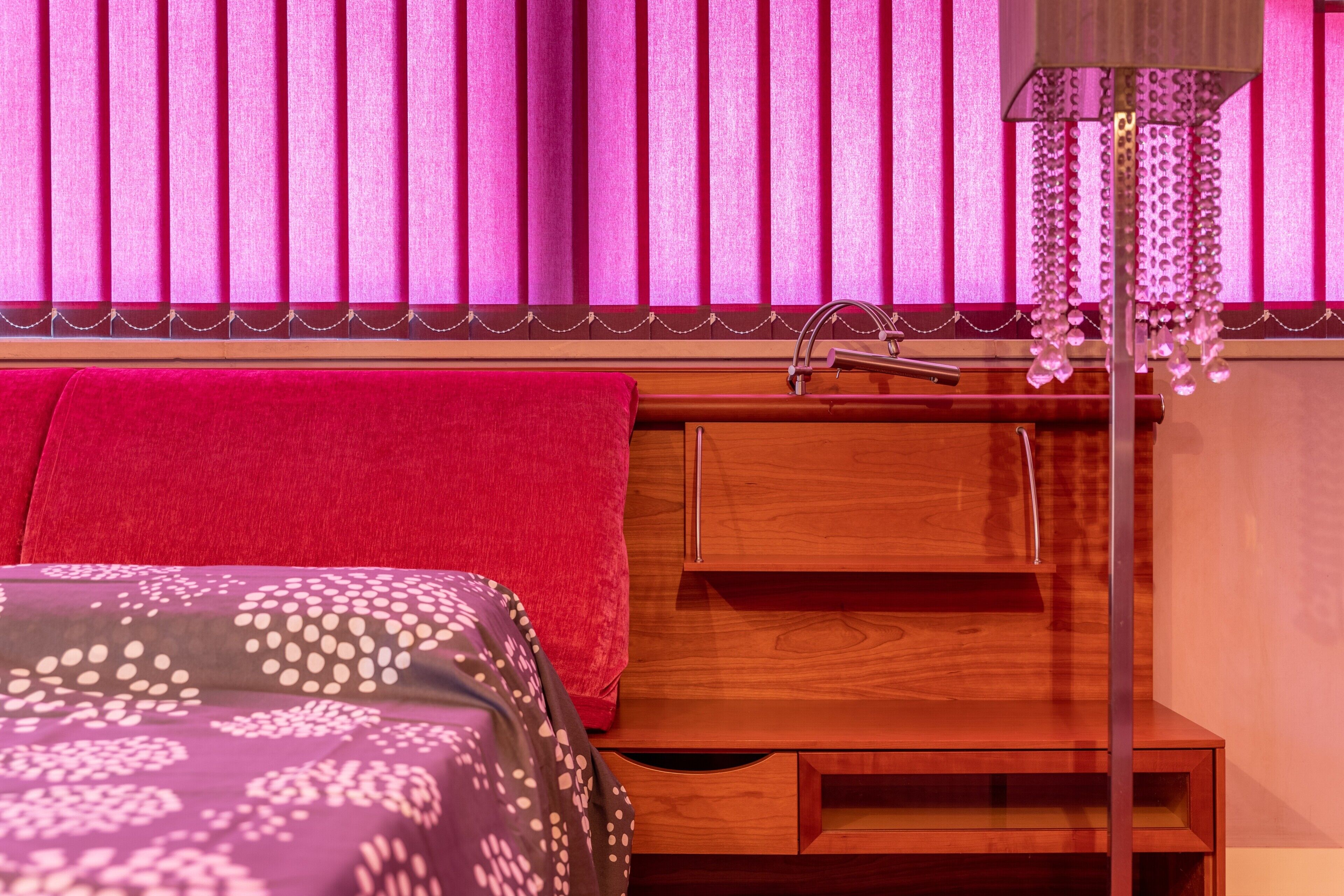 Un dormitorio con una cama, una mesita de noche de madera, un lavamanos y una lámpara colgante.