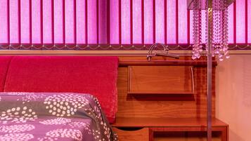 Un dormitorio con una cama, una mesita de noche de madera, un lavamanos y una lámpara colgante.