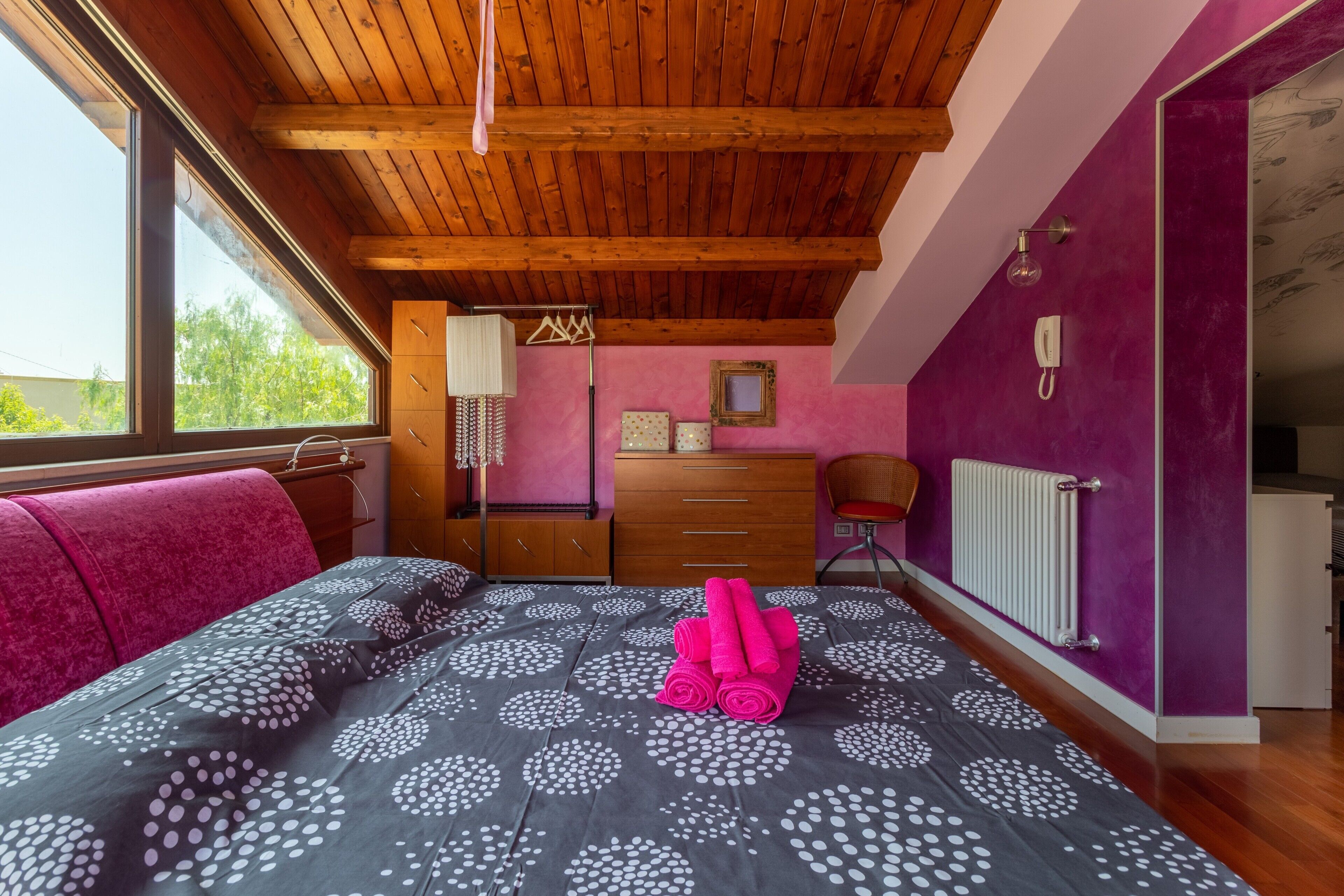 A bedroom with a bed, a dresser, a chair, a radiator, and a window.