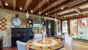 A rustic interior with a round table, white chairs, a clock, and a stone wall. - Apartment 'Giusa' with Shared Pool, Wi-Fi and Air Conditioning (Caltagirone)