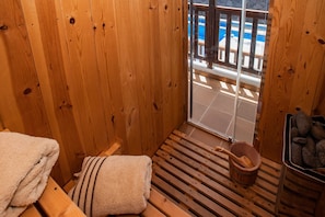 Un sauna en bois, avec un banc, une serviette, un seau et un récipient en pierre.