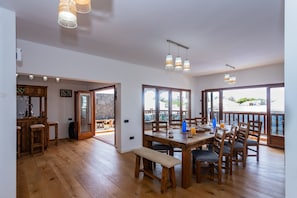 A spacious dining area with wooden furniture, large windows, and a view of the outdoors.