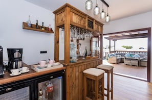 A bar area with a wooden structure, bar stools, a coffee machine, and a refrigerator.