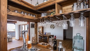 Una zona de bar con una grifo, vasos, botellas y un tarro grande.