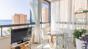 A balcony with a TV, a glass table, chairs, and a potted plant. - Apartment 'Apartamento Paraíso Florida' with Sea View, Wi-Fi and Air Conditioning (Benidorm)