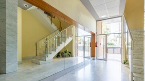 A spacious lobby with marble flooring, a glass staircase, and a view of the outside. - Apartment 'Apartamento Paraíso Florida' with Sea View, Wi-Fi and Air Conditioning (Benidorm)