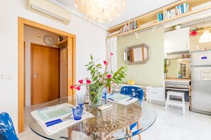 A dining area with a glass table, wicker chairs, a vase with flowers, and a kitchen in the background. - Apartment 'Apartamento Paraíso Florida' with Sea View, Wi-Fi and Air Conditioning (Benidorm)