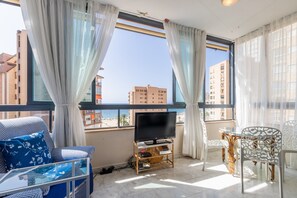 A balcony with a TV, seating, and a view of buildings and the sea. - Apartment 'Apartamento Paraíso Florida' with Sea View, Wi-Fi and Air Conditioning (Benidorm)