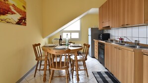 A kitchen with wooden cabinets, a dining table with chairs, and a window with a view. - Holiday Apartment "Corbezzolo" with Balcony & Shared Terrace (Bari sardo)