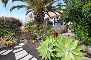 A garden with a palm tree, stepping stones, and various plants. - Holiday Home "Casa Titi" with Sea View, Private Terrace and Wi-Fi (La Palma)
