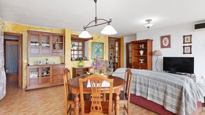 Una habitación con una mesa de comedor, sillas, un sofá, un televisor y un armario de madera.