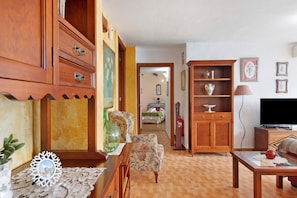 Un salon avec des meubles en bois, un téléviseur et un couloir menant à une chambre à coucher.