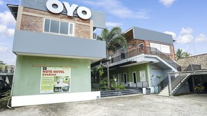 A hotel named OYO with a green facade, a signboard, and a staircase leading to a second floor. - OYO Life 91027 Note Hotel Syariah (Prabumulih)