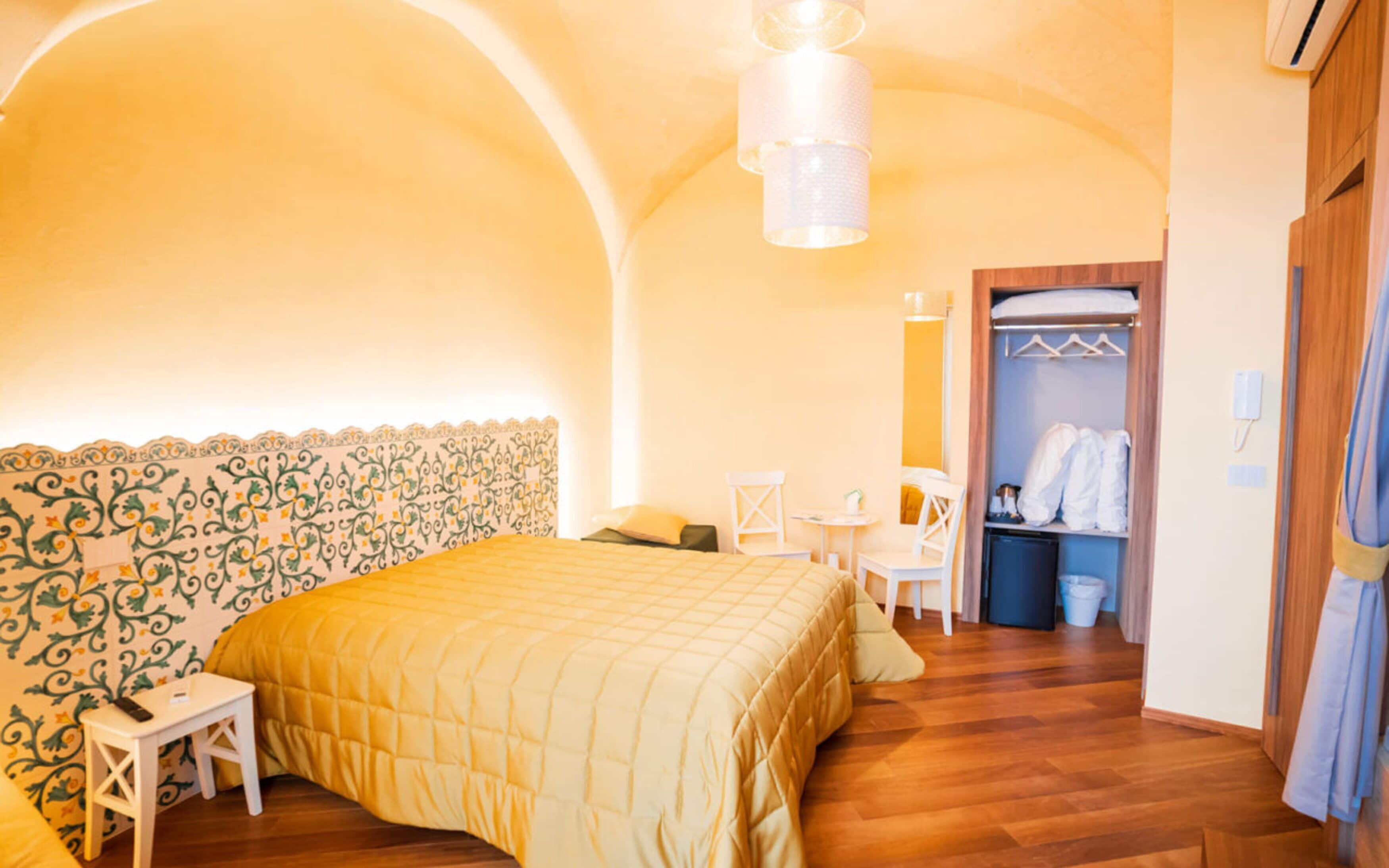 A bedroom with a bed, a small table, a chair, a wardrobe, and a mirror.
