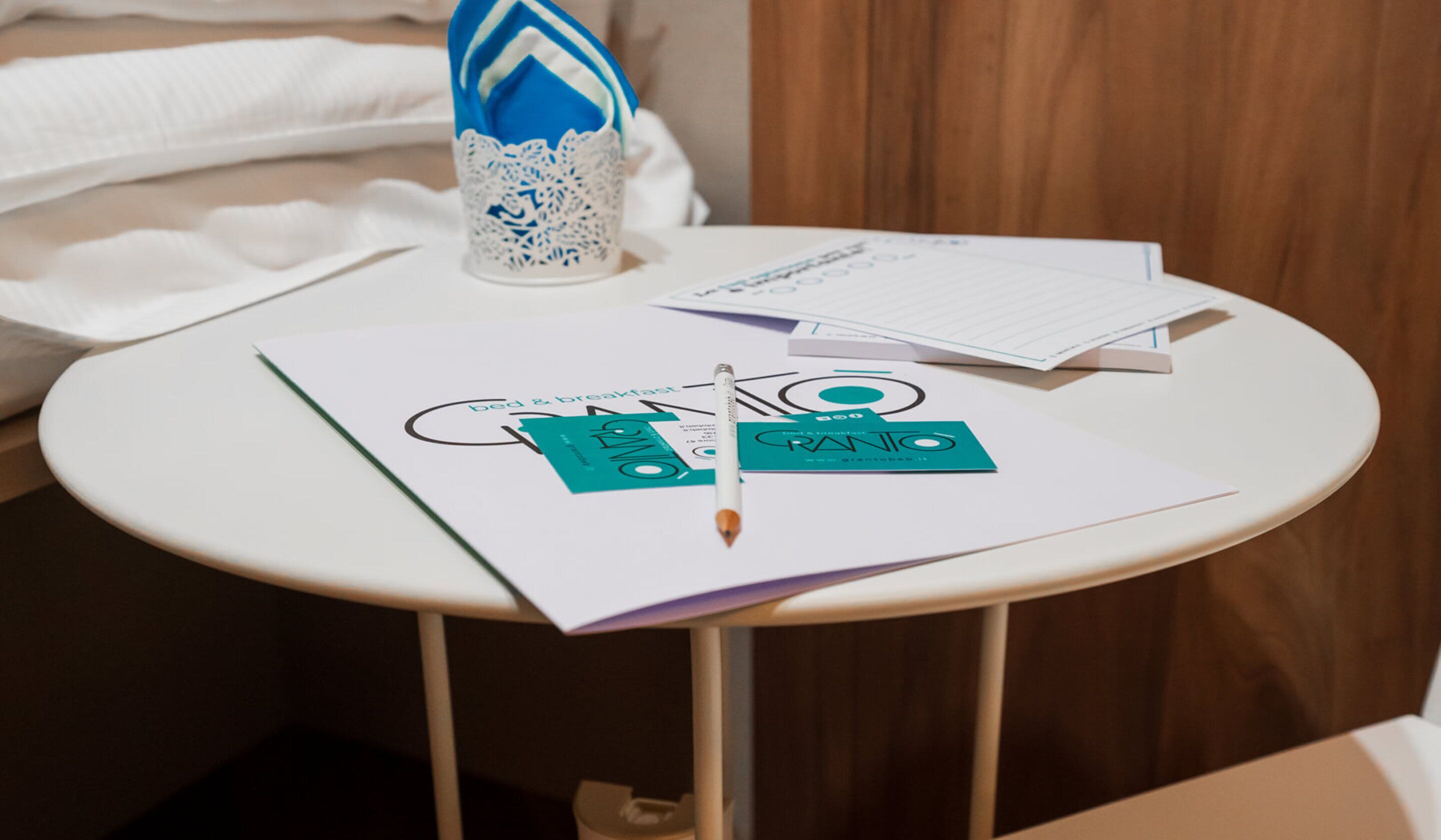 A small round table with a white tablecloth, a pen, and some papers with text and logos.