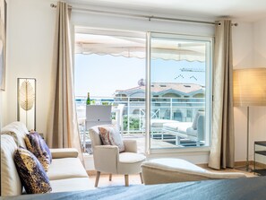 Een hotelkamer met een grote schuifdeur die leidt naar een balkon met buitenmeubilair.
