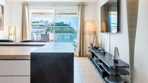 Ein modernes Hotelzimmer mit Balkon, einem Essbereich und einem an der Wand montierten Fernseher.