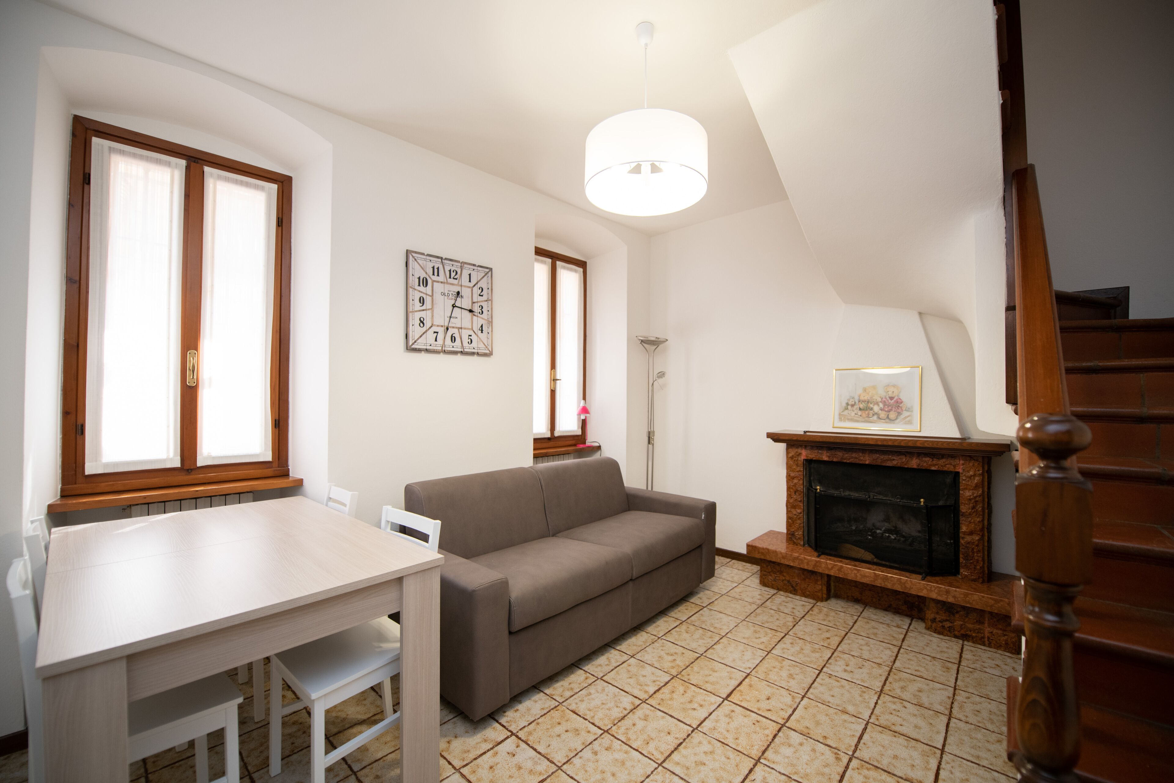 Un salon comprenant un canapé, une table à manger, une cheminée et un escalier.