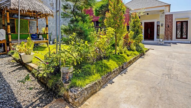 A garden area with a variety of plants and a thatched-roof structure. - Hotel O Reva Residence Syariah (Kamal)