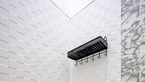 A bathroom with a large speckled ceramic sink, white tiled walls, a marble accent wall, and a black towel rack. - Hotel O Reva Residence Syariah (Kamal)