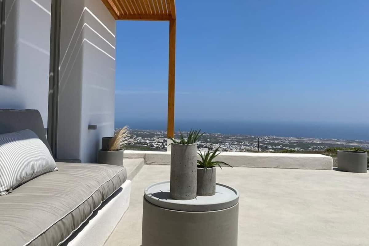 Ein moderner Balkon mit einer Sitzecke, zwei Topfpflanzen und Meerblick.