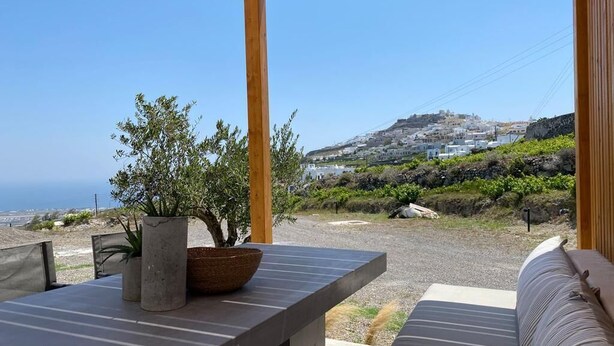 Zona d'estar a l'aire lliure coberta amb vista a una població costanera i un turó.