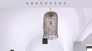Zona de dinar amb taula de fusta i cadires de fibra natural, llum penjant i paret blanca amb finestra.