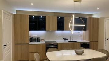 A modern kitchen with wooden cabinets, a white countertop, and a dining area with a marble table and chairs.
