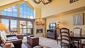 A spacious living room with a fireplace, large windows, a dining area, and a cozy seating arrangement. - Saint James Place 416 (Beaver Creek)