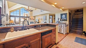 A spacious kitchen with a large island, a dishwasher, and a sink. There is a large mirror above the island, and a chandelier hanging from the ceiling. - Saint James Place 416 (Beaver Creek)