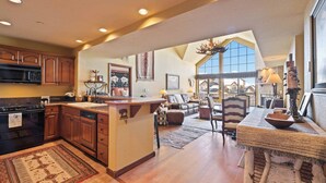 A spacious kitchen with wooden cabinets, a central island, and a large window providing a view of the outdoors. - Saint James Place 416 (Beaver Creek)