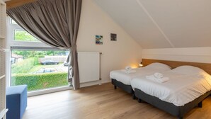 A bedroom with a large window, two beds, a radiator, and a view of a garden and parked cars. - Holiday Home near Beach Burgh-Haamstede (Burgh Haamstede)