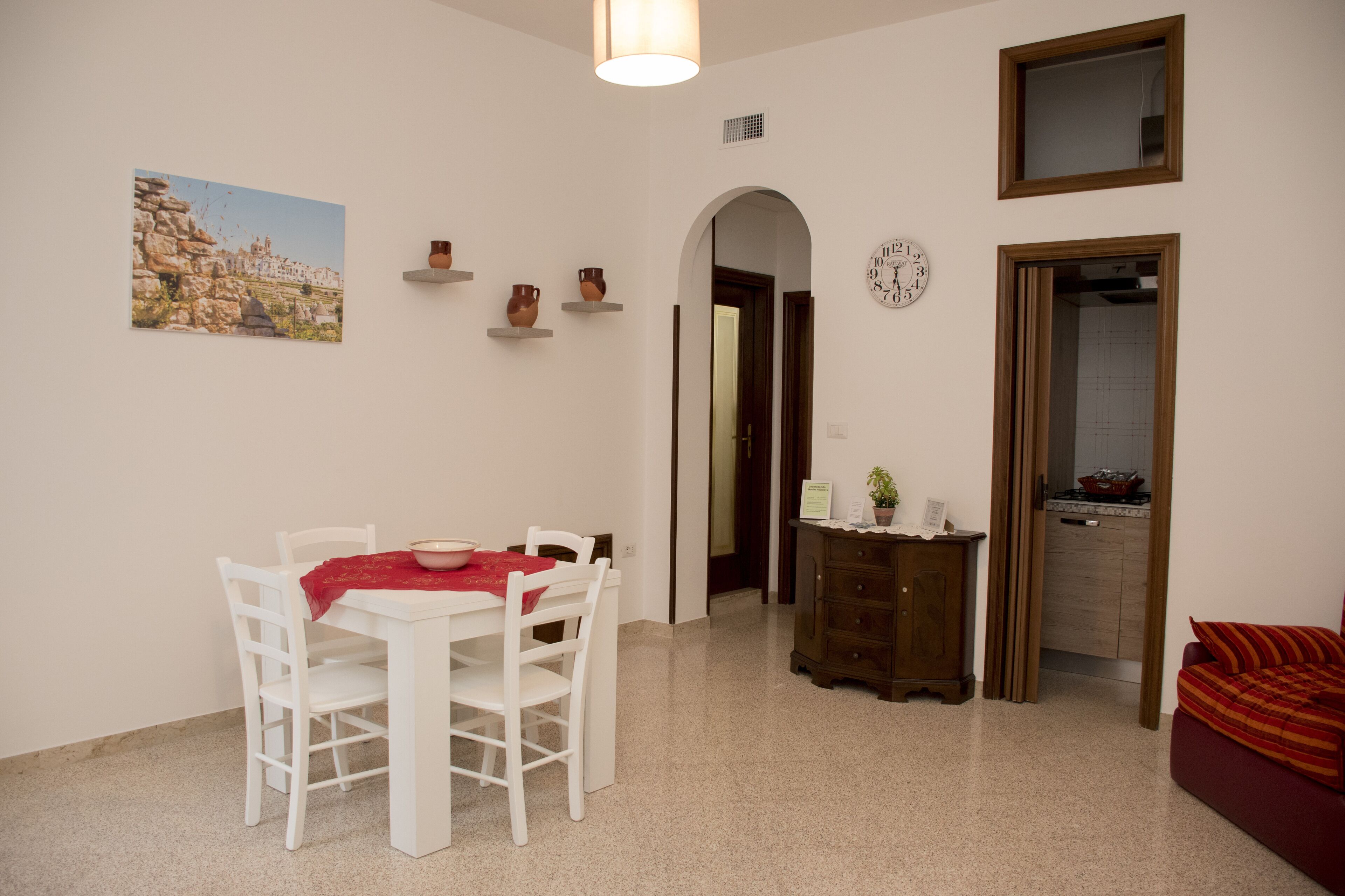 Un coin repas avec une table et des chaises, une horloge au mur et une vue sur la ville en arrière-plan.