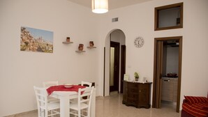 Un comedor con una mesa y sillas, un reloj en la pared y vistas de la ciudad al fondo.