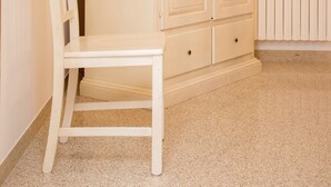 Una habitación con un armario blanco, una silla blanca y un radiador.