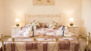 Una cama bien hecha con colcha, dos almohadas y dos lámparas de noche en mesitas de noche.