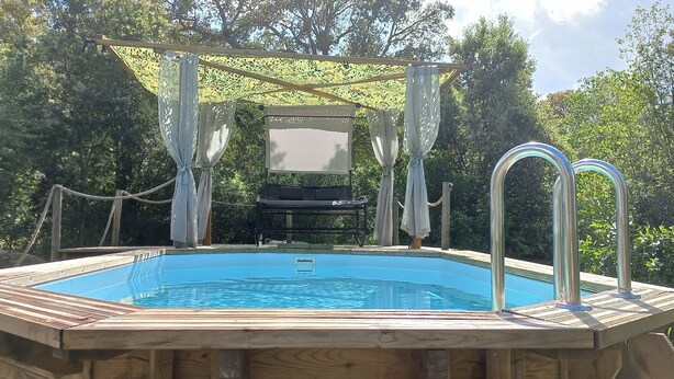 A wooden hot tub with a wooden deck and a pergola canopy.