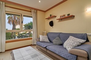 A living room with a sofa, pillows, a table, and a window with curtains.