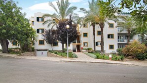 A multi-story building with balconies, palm trees, and a paved entrance area. - Apartment 'Tavirasol' with Shared Pool, Wi-Fi and Air Conditioning (Tavira)