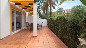 A patio with a tiled floor, a covered seating area, and a hedge. - Apartment 'Tavirasol' with Shared Pool, Wi-Fi and Air Conditioning (Tavira)
